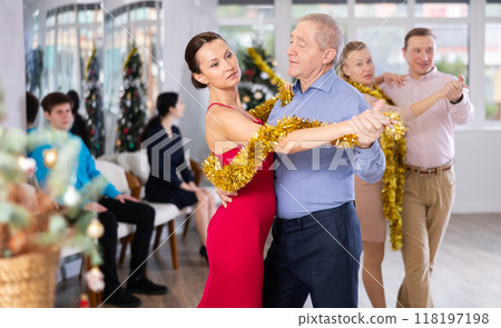 Couples dancing during Christmas - men and women dancing tango or samba next to Christmas tree 118197198