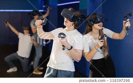 Emotional young couple with VR headsets and joysticks immersed in game Emotional young couple with VR headsets and joysticks immersed in game 118197298