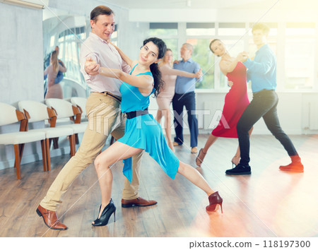 Portrait of adult pairs of different ages enjoying tango in modern dance hall together Portrait of adult pairs of different ages enjoying tango in modern dance hall together 118197300