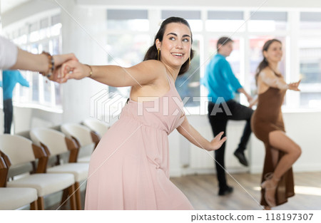 Couple in evening dresses enjoys pair dance boogie-woogie, interacting with each other on floor Couple in evening dresses enjoys pair dance boogie-woogie, interacting with each other on floor 118197307