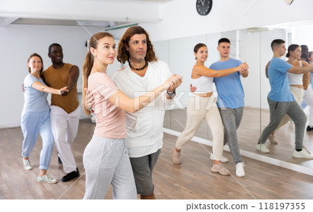 Portrait of positive adult couples dancing tango together in studio Portrait of positive adult couples dancing tango together in studio 118197355