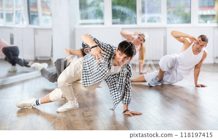Man and his students perform hip hop dance on one bent leg, movement in horizontal plane near floor Man and his students perform hip hop dance on one bent leg, movement in horizontal plane near floor 118197415