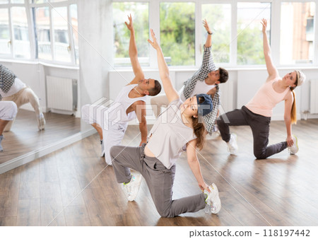 Girl and her students perform hip hop dance on one bent leg, movement in horizontal plane near floor Girl and her students perform hip hop dance on one bent leg, movement in horizontal plane near floor 118197442