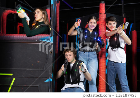 Two girls and two guys posing with lasertag guns in arena Two girls and two guys posing with lasertag guns in arena 118197455