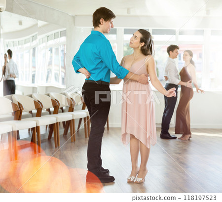 Happy girls paired with guys dance waltz in dance studio Happy girls paired with guys dance waltz in dance studio 118197523
