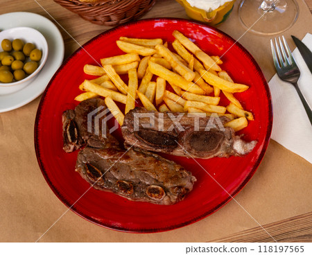On red plate-grilled beef ribs garnished with French fries 118197565