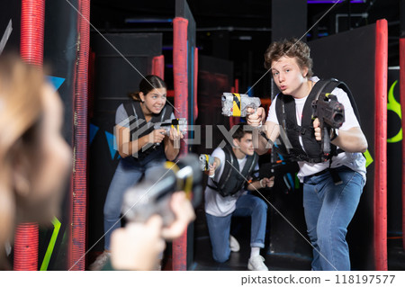 Three people having fun playing lasertag in arena Three people having fun playing lasertag in arena 118197577