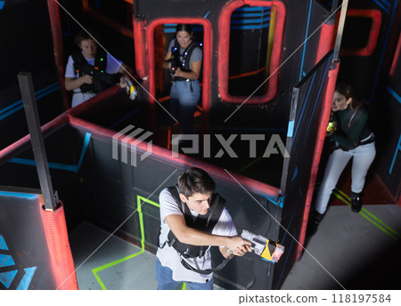 Four people having fun playing lasertag ducking behind cover in maze of lasertag arena Four people having fun playing lasertag ducking behind cover in maze of lasertag arena 118197584
