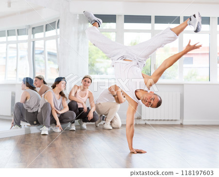 Young guy breakdancing in front of group members watching him 118197603