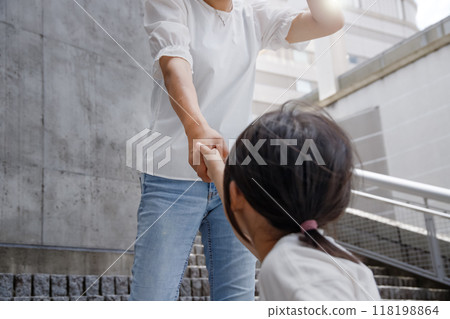 A woman holding a child's hand and walking up the stairs. Image of climbing to higher ground 118198864