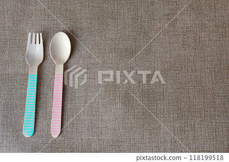 Wooden colorful spoons and forks on mat under plate. Disposable eco-friendly tableware. Food and snacking. Background for design. Wooden colorful spoons and forks on mat under plate. Disposable eco-friendly tableware. Food and snacking. Background for design. 118199518