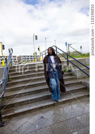 Woman confidently walks down urban stairs in chic outfit, embodying elegance and cosmopolitan style Woman confidently walks down urban stairs in chic outfit, embodying elegance and cosmopolitan style 118199850