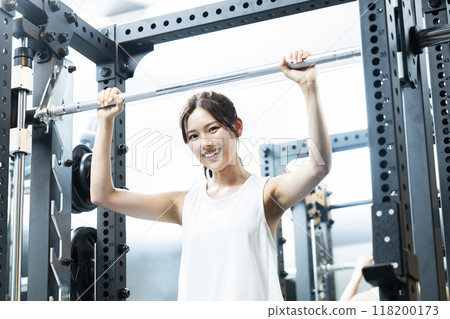 Young woman training at the gym, looking at camera, smiling Young woman training at the gym, looking at camera, smiling 118200173