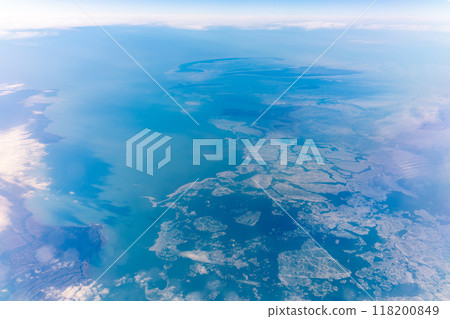 View from the airplane window at a beautiful blue clear sky, earth, sea and the airplane wing View from the airplane window at a beautiful blue clear sky, earth, sea and the airplane wing 118200849