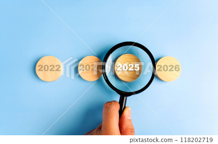 Man hand using magnifying glass focusing on word 2025 New Year concept. 118202719