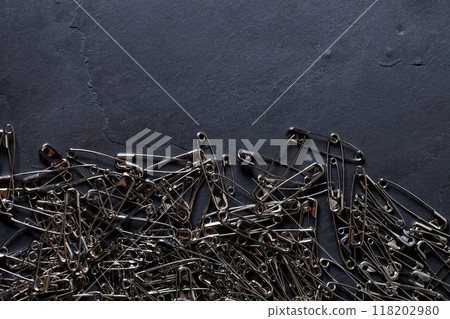 A number of stainless safety pins on black stone background. 118202980