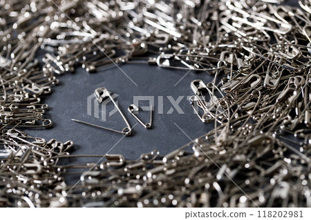 A number of stainless safety pins on black stone background. A number of stainless safety pins on black stone background. 118202981
