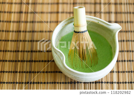 Cup of fresh matcha tea, green tea on wooden mat background. Selective focus. Cup of fresh matcha tea, green tea on wooden mat background. Selective focus. 118202982