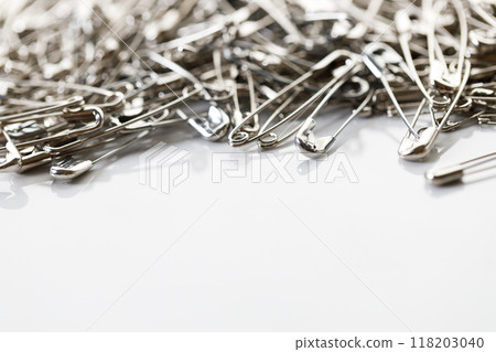 A number of stainless safety pins on white background. 118203040
