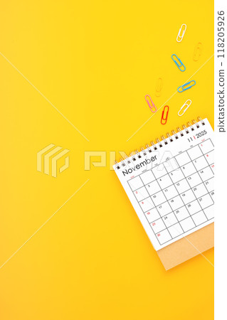 November 2025 desk calendar and paper clips on yellow background. Position with copy space. November 2025 desk calendar and paper clips on yellow background. Position with copy space. 118205926