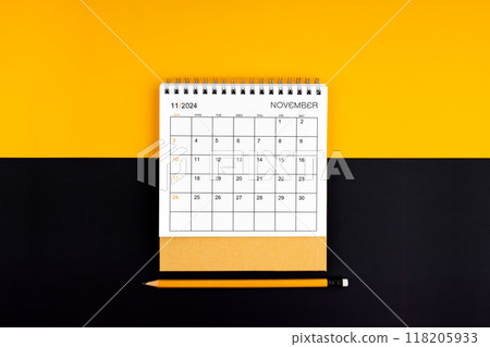 November 2024 desk calendar and pencil on yellow and black color background. 118205933