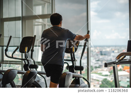 man doing exercise on an elliptical cross trainer in sport fitness gym man doing exercise on an elliptical cross trainer in sport fitness gym 118206368