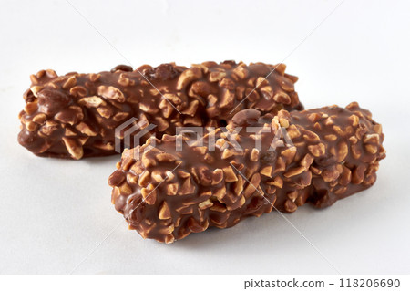 Two candy bars covered with peanuts and chocolate on a white table Two candy bars covered with peanuts and chocolate on a white table 118206690