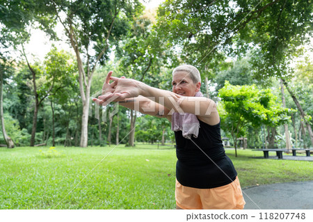 Elderly woman performing arm stretches in park Elderly woman performing arm stretches in park 118207748