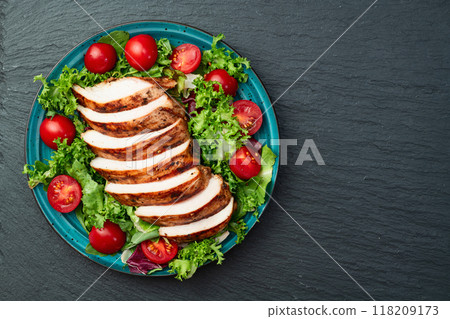 Grilled chicken breast ( fillet ) with lattuce salad and cherry tomatoes . Top view Grilled chicken breast ( fillet ) with lattuce salad and cherry tomatoes . Top view 118209173