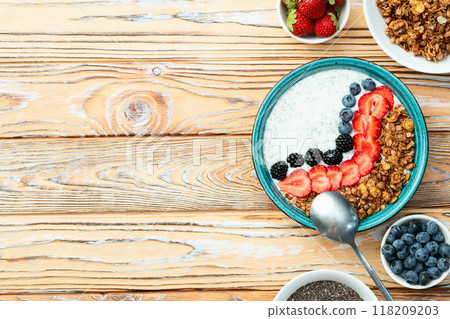 Healthy breakfast . Yogurt with berries ( strawberry , raspberry , blueberry , blackberry ) , granola and chia seeds . Top view Healthy breakfast . Yogurt with berries ( strawberry , raspberry , blueberry , blackberry ) , granola and chia seeds . Top view 118209203