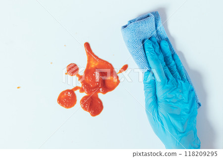 A person is cleaning a red stain on a white surface with a blue cloth A person is cleaning a red stain on a white surface with a blue cloth 118209295