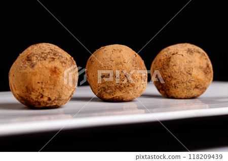 Beautiful candy truffle on a white plate on a black background 118209439