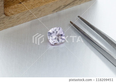 macro mineral faceted stone Morganite with tweezers on a gray background macro mineral faceted stone Morganite with tweezers on a gray background 118209451