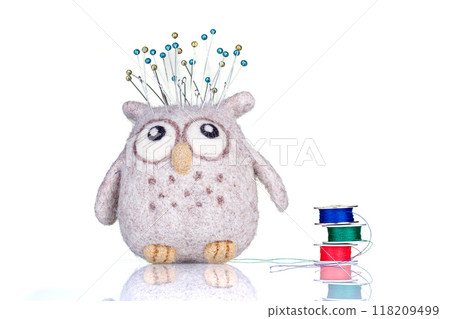 small pillow for needles in the form of an owl with threads on a white background 118209499