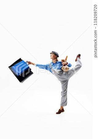 Woman leaps with bags swinging, as she joyfully embraces energy of lively shopping experience against white studio background. Woman leaps with bags swinging, as she joyfully embraces energy of lively shopping experience against white studio background. 118209720