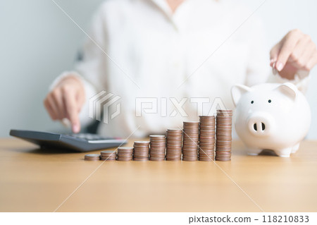 Money Saving for Future Plan, Retirement fund, Pension, Investment, Wealth Business and Financial concepts. Woman Counting and calculate money with coins stack with piggy bank for deposit 118210833