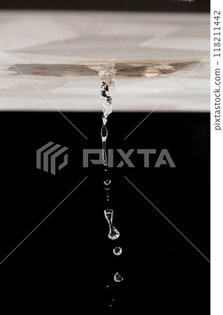 Ceiling Water leak from rain or broken pipe. House Water leaking on ceiling tile board and create dirty stain of flowing water, black background isolated 118211442