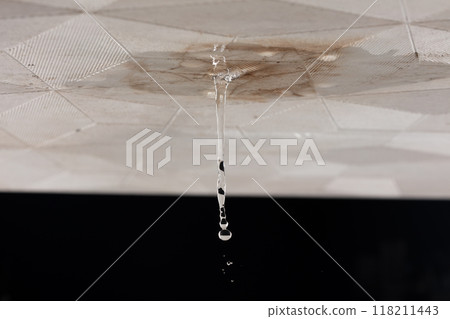 Ceiling Water leak from rain or broken pipe. House Water leaking on ceiling tile board and create dirty stain of flowing water, black background isolated 118211443