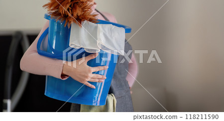 Housekeeper holding blue bucket with cleaning tools 118211590