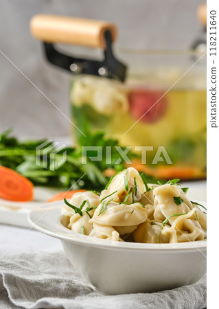 Pelmeni cooked in vegetable broth, close-up view 118211640