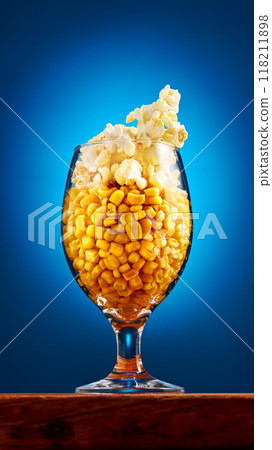 Beer glass filled with corn kernels and pop corn stands on table against blue studio background. Snacks and drinks for relax. Beer glass filled with corn kernels and pop corn stands on table against blue studio background. Snacks and drinks for relax. 118211898