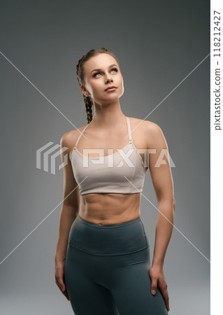 Fitness model posing confidently in athletic wear under studio lights 118212427