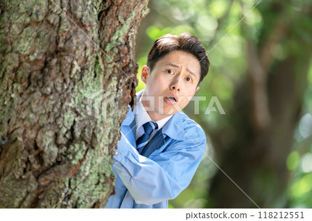 一名身穿工作服的男子躲在樹上 118212551