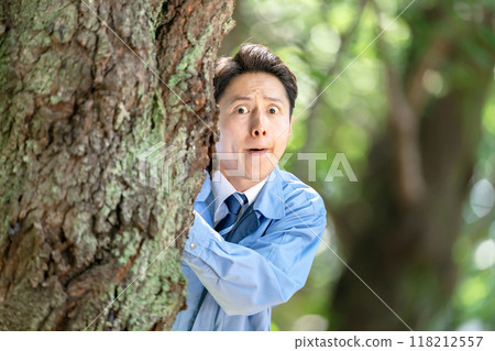 一名身穿工作服的男子躲在樹上 118212557