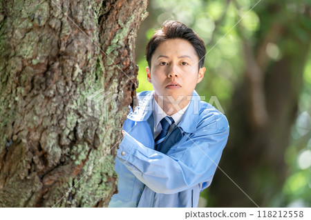 一名身穿工作服的男子躲在樹上 118212558