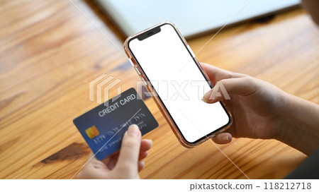 Close up shot of man holding a credit card and using internet banking application 118212718