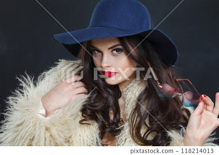 Portrait of woman with red lips make-up and long wavy hair wearing blue hat Portrait of woman with red lips make-up and long wavy hair wearing blue hat 118214013