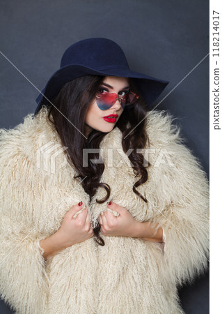 Healthy fashion model woman in blue classic hat and white fur coat posing indoor Healthy fashion model woman in blue classic hat and white fur coat posing indoor 118214017