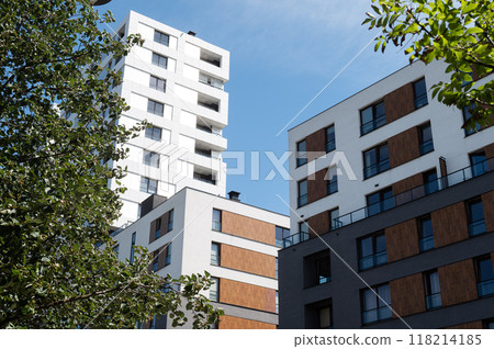 Modern apartment buildings with white and brown facade seen from below, surrounded by trees 118214185