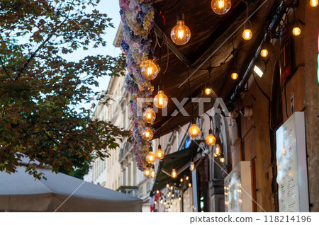 String lights hanging outside a cafe with flower decorations and trees. 118214196